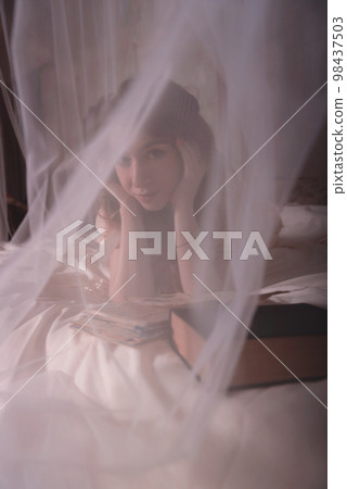 Beautiful woman with letter. A gentle photo of a woman on the bed. 98437503