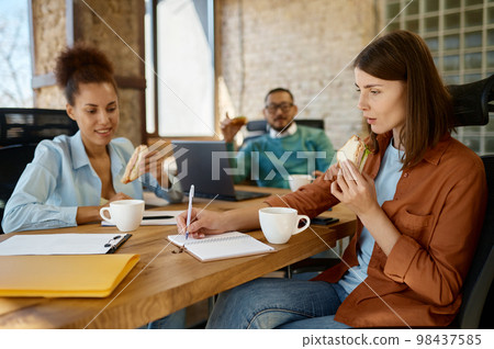 Businesspeople eating lunch together in coworking office 98437585