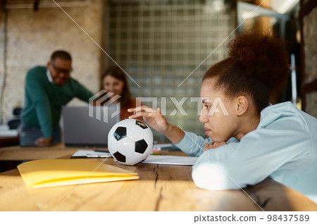 Pensive woman sitting at table in coworking space 98437589
