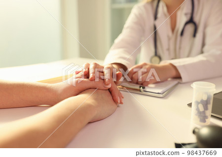 Doctor with his hand calming patient in clinic closeup 98437669