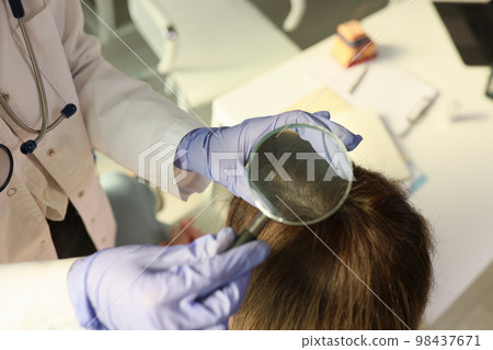 Doctor trichologist examining scalp of patient in clinic closeup Doctor trichologist examining scalp of patient in clinic closeup 98437671