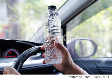 Asian woman driver hold cold water for drink in car, dangerous and risk an accident. Asian woman driver hold cold water for drink in car, dangerous and risk an accident. 98439161