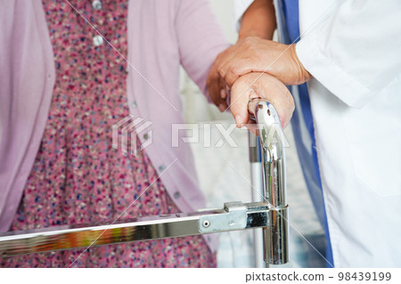 Doctor help Asian elderly woman disability patient walk with walker in nursing hospital, medical concept. Doctor help Asian elderly woman disability patient walk with walker in nursing hospital, medical concept. 98439199