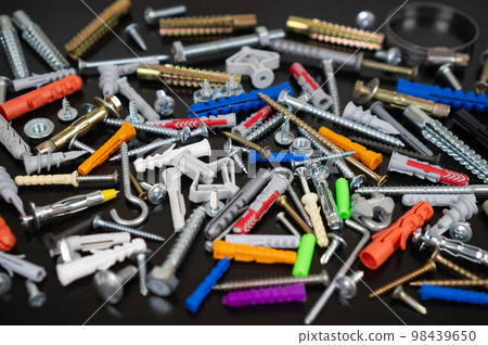Different types of fasteners on a dark wood background. Front view. 98439650
