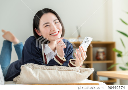 年輕女子在客廳看智慧型手機 年輕女子在客廳看智慧型手機 98440574