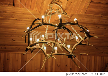 Chandelier on the ceiling made of deer antlers. A light bulb in the shape of a candle. Chandelier on the ceiling made of deer antlers. A light bulb in the shape of a candle. 98441004