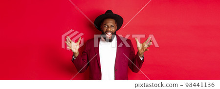 Angry Black man screaming and shaking hands with hatred, losing temper, standing outraged against red background 98441136