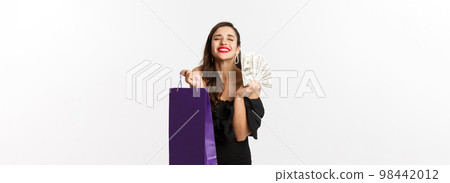 Satisfied and happy woman enjoying shopping, holding bag and money, smiling pleased, standing over white background Satisfied and happy woman enjoying shopping, holding bag and money, smiling pleased, standing over white background 98442012