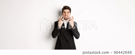 Image of angry businessman in suit, looking with furious expression and clenching fists, express hatred, standing mad over white background 98442699