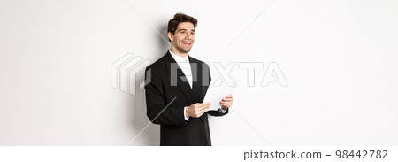 Image of handsome businessman in suit, holding documents and smiling, standing against white background 98442782
