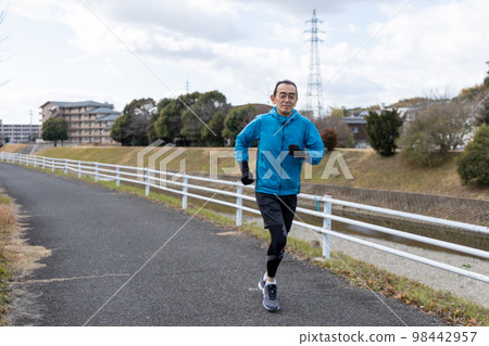 Senior man doing hobby jogging on riverside promenade on holiday 98442957