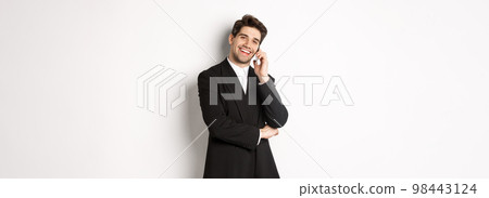 Image of handsome, successful businessman talking on phone, smiling pleased, standing in suit against white background 98443124