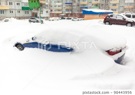 Car covered with snow, close-up. A passenger car in winter was covered with snow after a snow storm. Car in the parking lot near the house 98443956