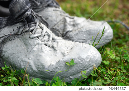 Shoes heavily stained in grey paint on the green grass Shoes heavily stained in grey paint on the green grass 98444887