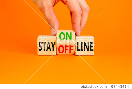 Stay online or offline symbol. Concept word Stay online or offline on wooden cubes. Businessman hand. Beautiful orange table orange background. Business and stay online or offline concept. Copy space. Stay online or offline symbol. Concept word Stay online or offline on wooden cubes. Businessman hand. Beautiful orange table orange background. Business and stay online or offline concept. Copy space. 98445414