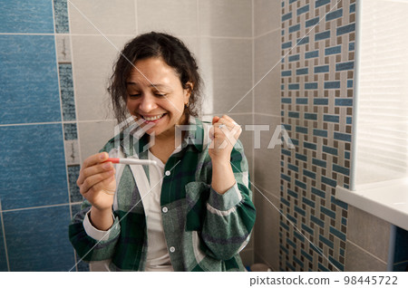 Charming multi-ethnic middle-aged woman, sitting on the toilet bowl in the home bathroom, rejoicing at positive pregnancy test. Finally pregnant. Gynecology, maternity, family and pregnancy concept Charming multi-ethnic middle-aged woman, sitting on the toilet bowl in the home bathroom, rejoicing at positive pregnancy test. Finally pregnant. Gynecology, maternity, family and pregnancy concept 98445722