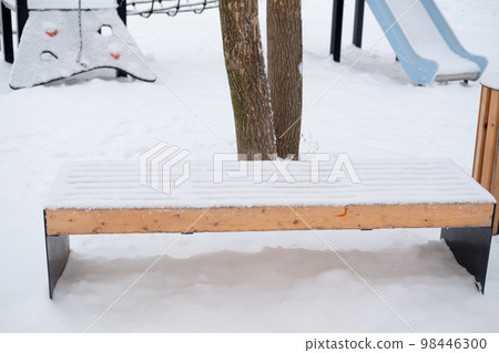 snow-covered empty bench on the street, on the playground snow-covered empty bench on the street, on the playground 98446300
