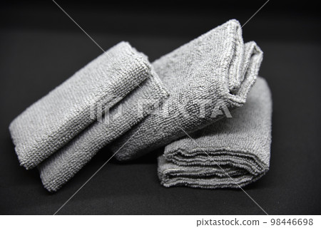 Three gray towels on a black background. Terry cloths for wiping furniture. Towels on a black background. Three gray towels on a black background. Terry cloths for wiping furniture. Towels on a black background. 98446698