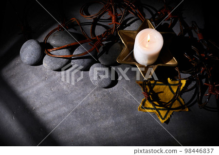 Holocaust memory day. Barbed wire, stones, yellow star and burning candle on black background Holocaust memory day. Barbed wire, stones, yellow star and burning candle on black background 98446837