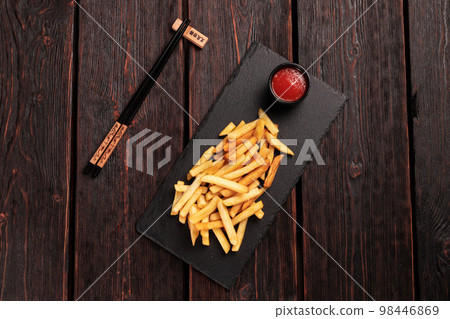 French fries with ketchup on dark wooden background top view - fast food and unhealthy eat concept French fries with ketchup on dark wooden background top view - fast food and unhealthy eat concept 98446869