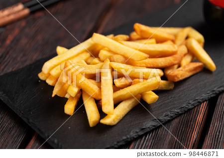 French fries on dark wooden background - fast food and unhealthy eat concept French fries on dark wooden background - fast food and unhealthy eat concept 98446871