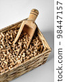 Hardwood Pellets used in pellet wood stoves in a wicker box and wooden scoop 98447157