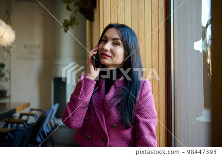 Caucasian confident stylish middle-aged brunette woman, businesswoman, chief executive, CEO, purposeful entrepreneur talking on mobile phone and looking at camera. People. Lifestyle. Business call Caucasian confident stylish middle-aged brunette woman, businesswoman, chief executive, CEO, purposeful entrepreneur talking on mobile phone and looking at camera. People. Lifestyle. Business call 98447393