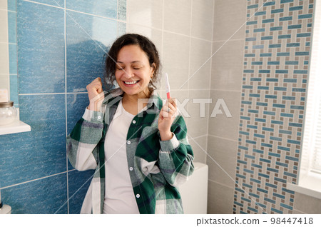 Middle-aged smiling woman with positive pregnancy test in the home bathroom Middle-aged smiling woman with positive pregnancy test in the home bathroom 98447418