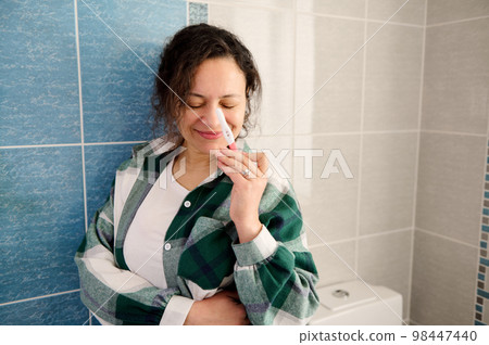 Cheerful happy woman smiling while holding positive pregnancy test Cheerful happy woman smiling while holding positive pregnancy test 98447440