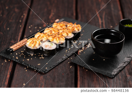 Maki sushi roll with eel and cucumber served on black board close-up - Japanese food Maki sushi roll with eel and cucumber served on black board close-up - Japanese food 98448136