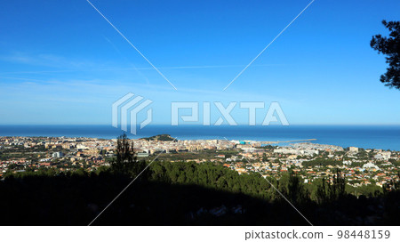 Panoramic view from height of Mediterranean resort seaside town Denia, roofs of the houses, sea in the distance, beautiful landscape 98448159