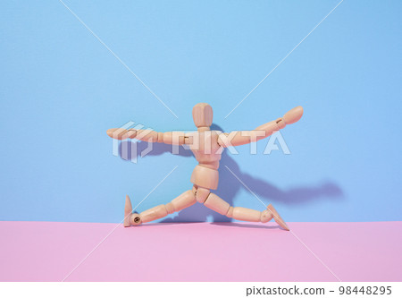 Wooden puppet man on a blue background, a pose in a twine. Sports Wooden puppet man on a blue background, a pose in a twine. Sports 98448295