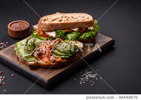 Fresh tasty sandwich with salmon, avocado and sesame and flax seeds 98448676