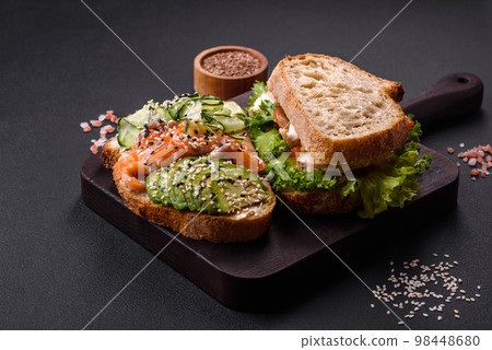 Fresh tasty sandwich with salmon, avocado and sesame and flax seeds 98448680