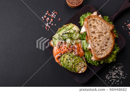 Fresh tasty sandwich with salmon, avocado and sesame and flax seeds 98448682