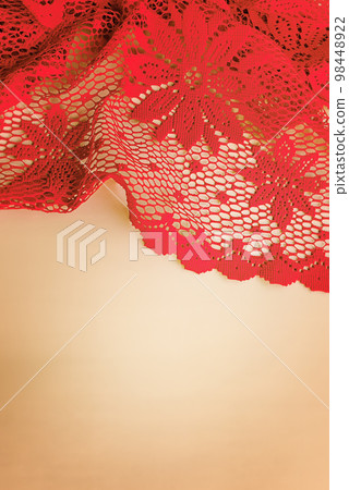 Lace knitted red fabric on a beige background. Checkered red tablecloth. 98448922