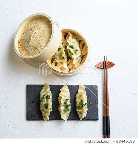 steamed dumpling or Japanese gyoza, dumplings snack in traditional wooden steamer and black stone slate on white texture stone background top view steamed dumpling or Japanese gyoza, dumplings snack in traditional wooden steamer and black stone slate on white texture stone background top view 98449199
