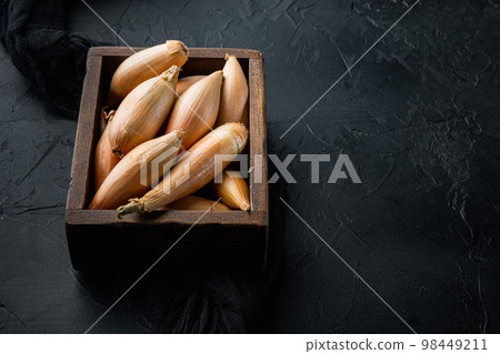 Raw baby shallot onion, on black textured background with space for text Raw baby shallot onion, on black textured background with space for text 98449211