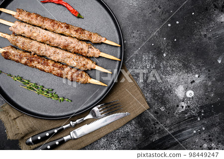 Tikka, shish and kofta kebabs, on plate, on black dark stone table background, top view flat lay, with copy space for text Tikka, shish and kofta kebabs, on plate, on black dark stone table background, top view flat lay, with copy space for text 98449247