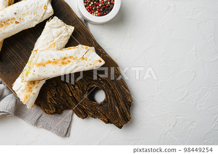 Doner kebab, shawarma with vegetables, on cutting board, on white stone table background, Doner kebab, shawarma with vegetables, on cutting board, on white stone table background, 98449254