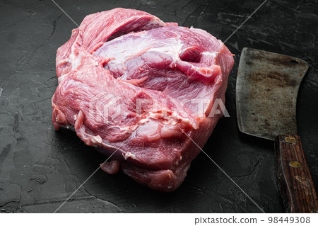 Pork meat shoulder , with old butcher cleaver knife, on black dark stone table background 98449308