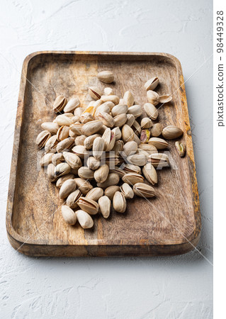 Shelled unsalted pistachios, on white textured background Shelled unsalted pistachios, on white textured background 98449328
