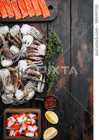 Fresh Crab meat and sticks surimi with blue swimming crab, on dark wooden background, top view flat lay , with copyspace and space for text Fresh Crab meat and sticks surimi with blue swimming crab, on dark wooden background, top view flat lay , with copyspace and space for text 98449398