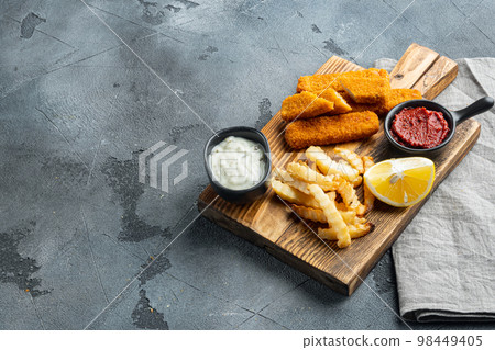 Fried fish finger stick or french fries fish with sauce, on wooden cutting board, on gray background , with copyspace and space for text Fried fish finger stick or french fries fish with sauce, on wooden cutting board, on gray background , with copyspace and space for text 98449405