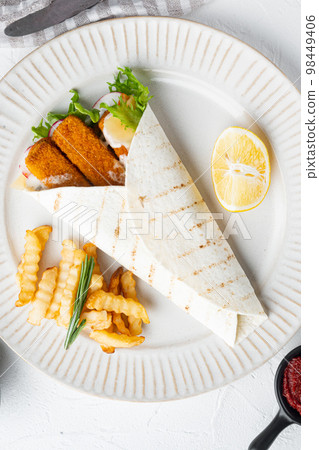 Sandwich roll with fish fingers, cheese and vegetables, on plate, on white background, top view flat lay Sandwich roll with fish fingers, cheese and vegetables, on plate, on white background, top view flat lay 98449406