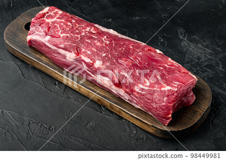 Tenderloin, or Eye Fillet cut raw marbled beef meat, on black stone background, with copy space for text 98449981