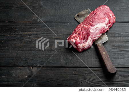 Beef fillet mignon cut raw , with old butcher cleaver knife, on black wooden table background, with copy space for text Beef fillet mignon cut raw , with old butcher cleaver knife, on black wooden table background, with copy space for text 98449985