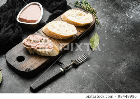 Fresh chicken liver pate from can on bread, on black dark stone table background, with copy space for text 98449986