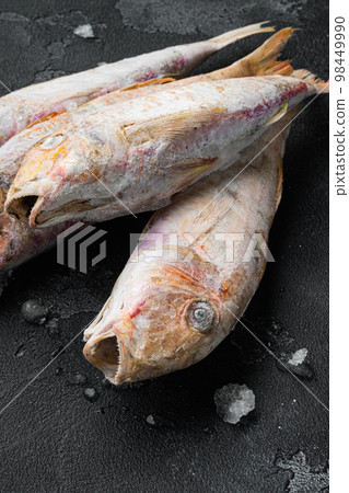Frozen red mullet or barabulka raw fish, on black dark stone table background 98449990