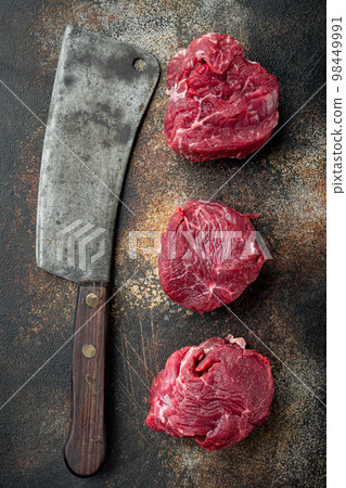 Raw beef fillet steaks with spices, and old butcher cleaver knife, on old dark rustic background, top view flat lay 98449991